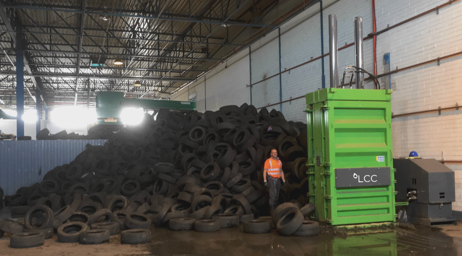 Montaña de neumáticos usados en planta de reciclaje con prensa de residuos LCC V85.